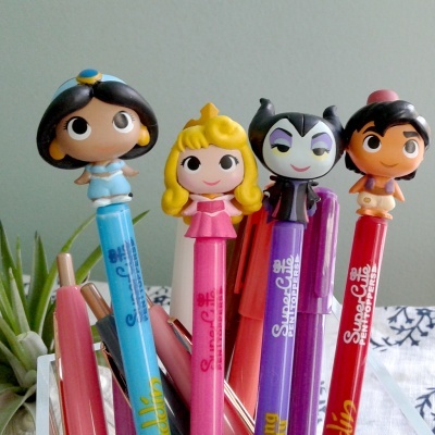 Canetas coloridas com personagens de desenhos animados nas tampas em recipiente
