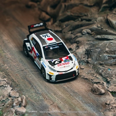 Miniatura de carro de rali branco com número 34 e logotipos em terreno simulado rochoso