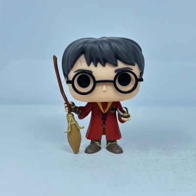 Funko Pop do Harry Potter de capa vermelha segurando vassoura e Bola de Ouro
