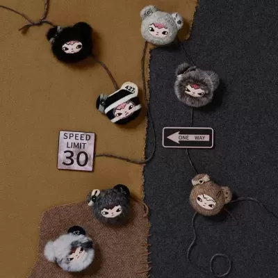 Sete bonecos de tecido com rostos e orelhas de ursinho em tecido castanho e cinza com placas de sinais