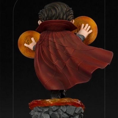 Figura de personagem com capa vermelha e base de pedra cinzenta
