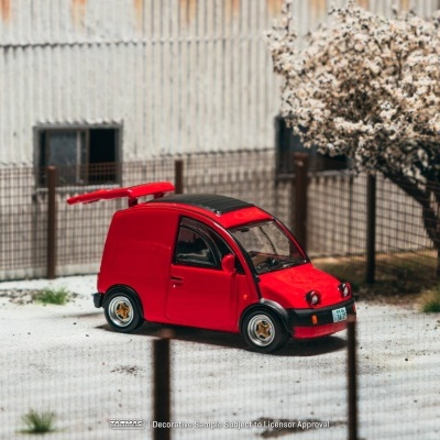 Miniatura de carro vermelho em ambiente urbano com cerca metálica