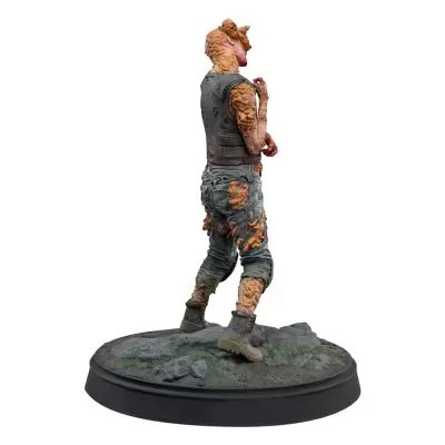Figura de personagem com pele ferida e roupas em base rochosa