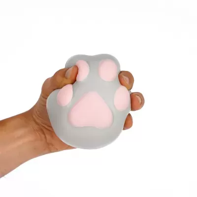 Brinquedo anti-stress cinzento e rosa em forma de pata animal, segurado por mão