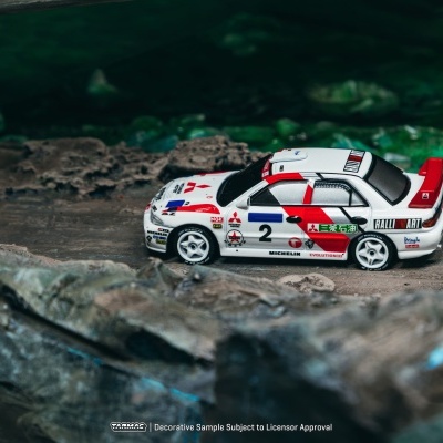 Miniatura de carrinha de corrida Mitsubishi branca com detalhes vermelhos e pretos sobre superfície rochosa