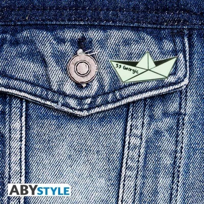 Broche em forma de barquinho de papel colocado num bolso de camisa de ganga azul.