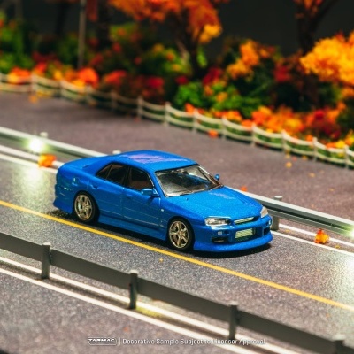 Carro desportivo azul metálico em estrada miniatura com árvores de outono