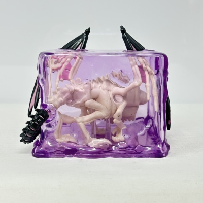 Esqueleto de dinossauro cor-de-rosa dentro de resina roxa translúcida com detalhes pretos.