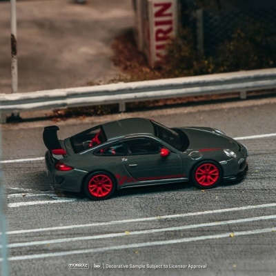Miniatura de carro desportivo cinza com detalhes vermelhos numa superfície de estrada.