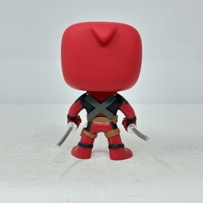 Figura colecionável vermelha vista de costas segurando espadas