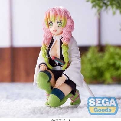 Figura colecionável anime com cabelo rosa e verde ajoelhada numa superfície branca