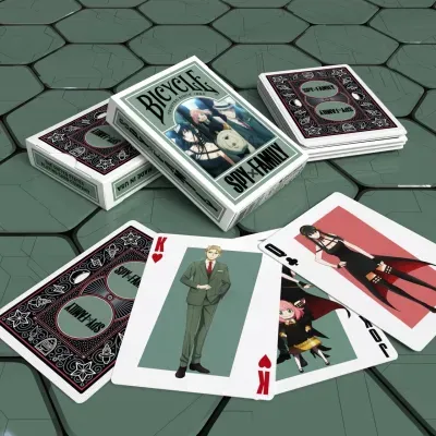 Baralho de cartas BICYCLE SPY x FAMILY com personagens de anime e cartas abertas em superfície hexagonal verde