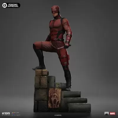 Figura de ação Daredevil em fato vermelho sobre degraus de pedra com pôster de rosto assustador