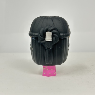 Figura colecionável de boneca com cabelo preto e saia rosa com bolinhas douradas vista de trás