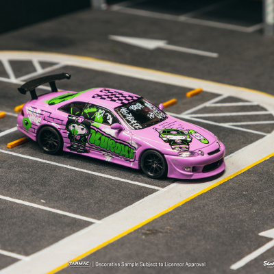 Carro de brinquedo rosa com gráficos coloridos numa miniatura de parque de estacionamento