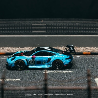 Modelo de carro de corrida azul com inscrições e pneus Goodyear em pista com barreira preta e amarela