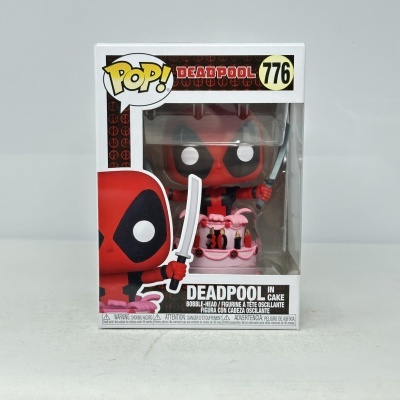 Boneco Funko Pop! Deadpool número 776 em caixa com Deadpool em cima de bolo rosa.