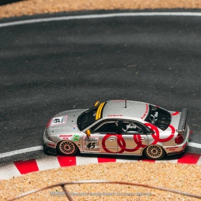 Miniatura de carro de corrida prateado com detalhes vermelhos numa pista de corrida em miniatura