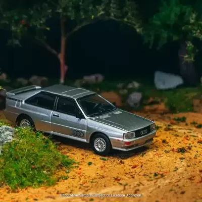 Miniatura de carro Audi prateado num cenário natural em miniatura.