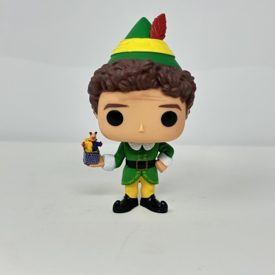 Figura Funko Pop de personagem vestido com chapéu verde, casaco verde, calças amarelas e sapatos pretos, segurando pequena figura.