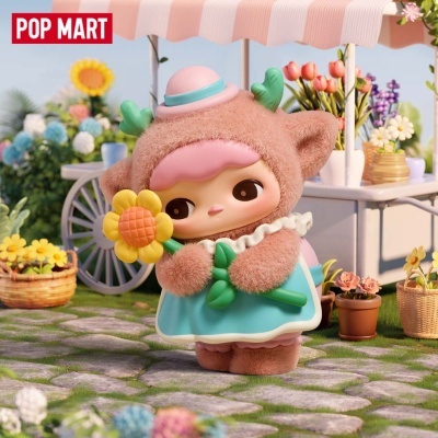 Boneca colecionável fofa em vestido azul e fato peludo castanho segurando flor no jardim.