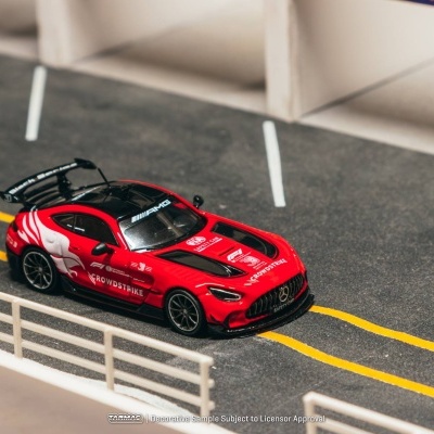 Miniatura de carro desportivo vermelho e preto numa pista com linhas e guarda branca