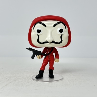 Figura colecionável com máscara branca e fato vermelho segurando arma em base transparente.