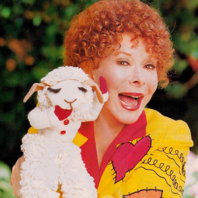 Mulher de cabelo ruivo segura marioneta de ovelha de pelúcia branca