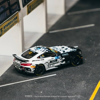 Miniatura de carro de corrida preto e branco em cenário de circuito com placas Macau Grand Prix