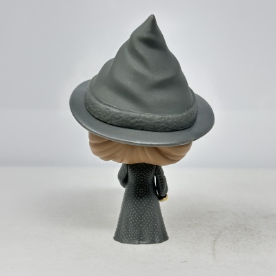 Figura de vinil de bruxa vista de costas com chapéu cinzento e vestido cinzento