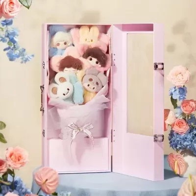 Caixa rosa aberta com buquê de peluches sorridentes e flores ao redor