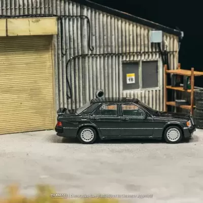Miniatura de carro preto em garagem simulada com porta amarelo e pneus.