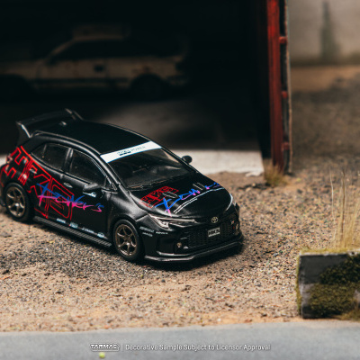 Miniatura de carro preto decorado com grafismos coloridos em chão de gravilha