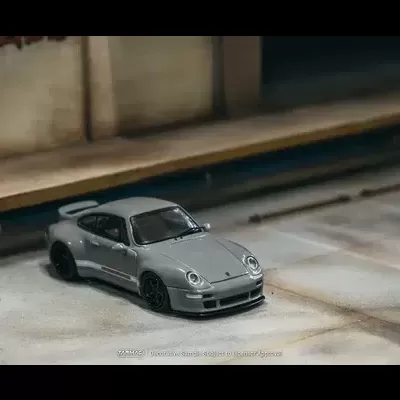 Miniatura de carro desportivo cinzento num piso de estacionamento.