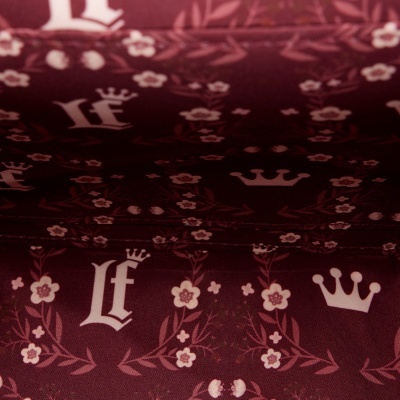 Tecido castanho escuro com padrão de coroas, flores e letras Lf