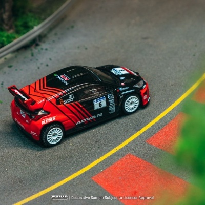 Miniatura de carro de rally preto e vermelho em pista de corrida com marcas amarelas e vermelhas
