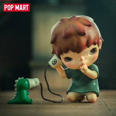Figura decorativa de menino a sussurrar para um dinossauro com megafone.