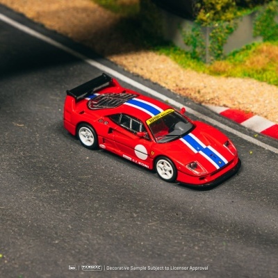 Miniatura de carro Ferrari vermelho com faixas azuis e brancas numa pista de corrida em miniatura