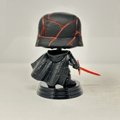 Figura Funko Pop preta com capa e capacete com linhas vermelhas, espada vermelha, suporte preto