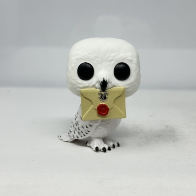 Figura de coruja branca com carta na boca e selo vermelho