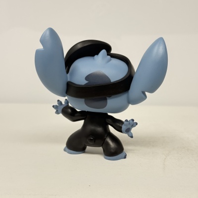 Figura de vinil azul com orelhas grandes vestida de preto vista por trás