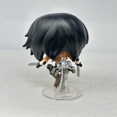 Figura colecionável com cabelo preto e roupa castanha em suporte transparente
