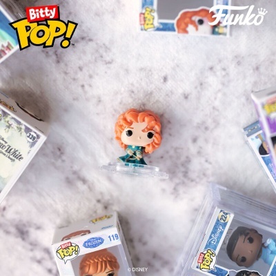 Figura Funko Pop! Bitty com cabelo ruivo e vestido azul rodeada por caixas de Funko