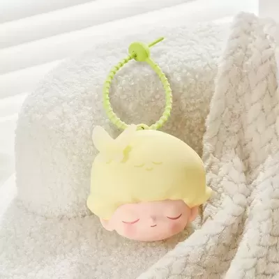 Chaveiro amarelo com cabeça de boneco e borboleta, com argola verde, sobre tecido felpudo bege