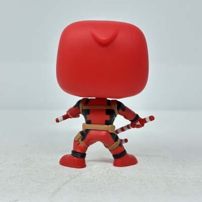 Boneco Funko Pop Deadpool visto de costas com armas nas mãos.