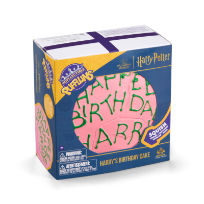 Caixa azul e amarela com bolo cor de rosa e texto verde 'HAPPY BIRTHDAY HARRY' visível