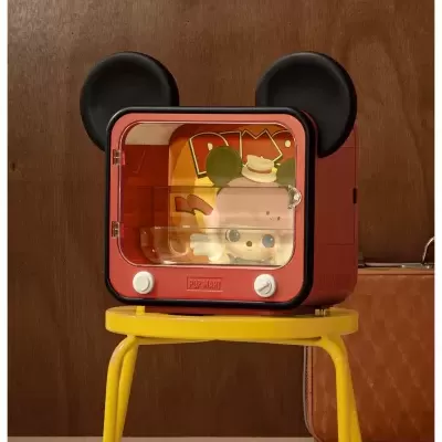 Mini geladeira vermelha com orelhas de rato e porta transparente sobre banco amarelo