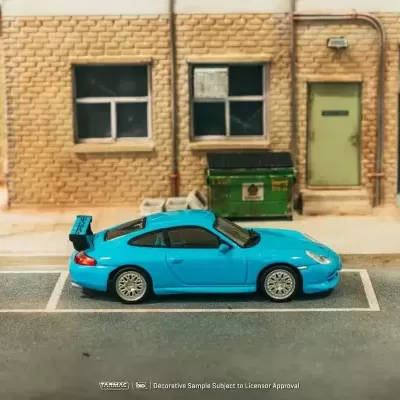Miniatura de carro azul estacionado em frente a parede de tijolos com janelas e porta