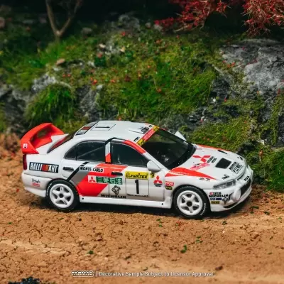 Miniatura de carro de rali branco com detalhes vermelhos e pretos num cenário de terra e vegetação
