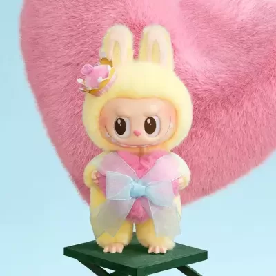 Boneca colecionável com fato de coelho amarelo e coroa rosa com coração e laço azul